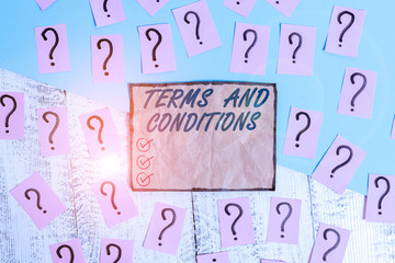 Writing note showing Terms And Conditions. Business concept for rules that apply to fulfilling a particular contract Scribbled and crumbling papers with thick cardboard above wooden table