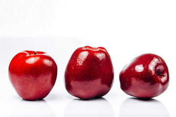 A few fresh red apples on a white background with a beautiful reflection