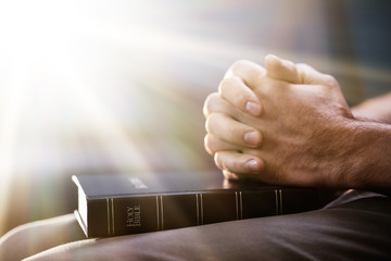 Man's Praying Hand On Bible