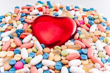 Fototapeta na wymiar Assorted pharmaceutical medicine pills, tablet, and figurine in the shape of a heart. Pills background. Heap of various assorted medicine tablets and pills different colors on white background.