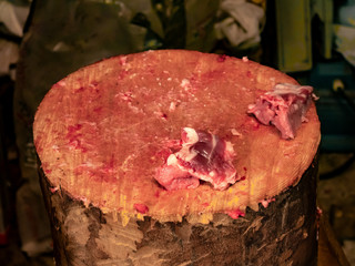 Pieces of meat on a large wooden log full of blood after cutting pork