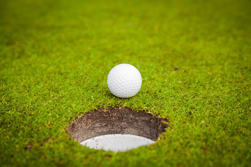 golf ball on lip of cup. Golf ball on green grass in golf course