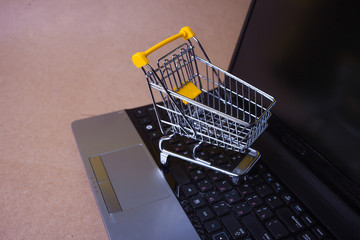 Buy now, Shopaholic on the Internet. Online shopping, shopping cart on laptop keyboard.