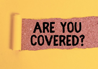 Word writing text Are You Covered Question. Business photo showcasing asking showing if they had insurance in work or life Cardboard which is torn in the middle placed above a wooden classic table