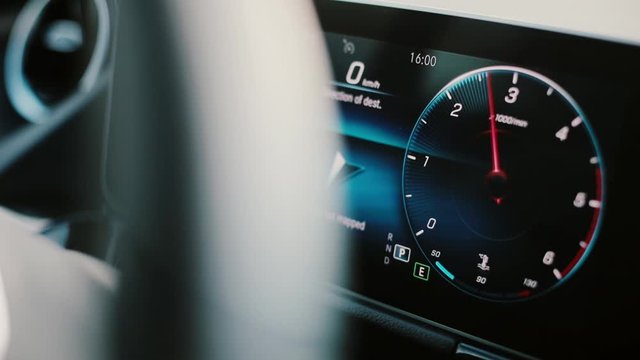 Close up footage of the digital display of a modern car, with a revving tachometer. 