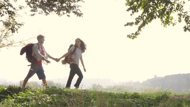 Young lovely couple backpackers tourists walking holding hands arrive on hill in front of roman aqueduct arches in parco degli acquedotti park ruins in rome on romantic misty sunrise with guitar and