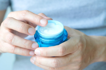 Hand of woman holding moisturizer cream and serum. She applying a facial cream , essential , oil , lotion and body cream for skin care, close up view and blur background. Beauty and Healthy Concept.