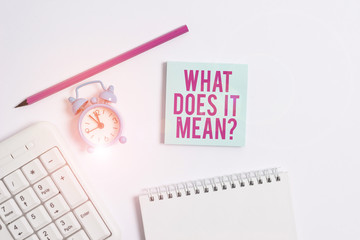 Handwriting text writing What Does It Mean question. Conceptual photo intended to communicate unclear statement White pc keyboard with empty note paper and pencil above white background