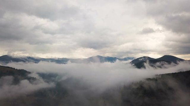 4K .Aerial. Real fly over mountain clouds, gloomy day, hills with wood.Landscape
