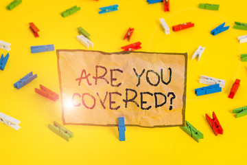 Handwriting text writing Are You Covered Question. Conceptual photo asking showing if they had insurance in work or life Colored clothespin papers empty reminder yellow floor background office