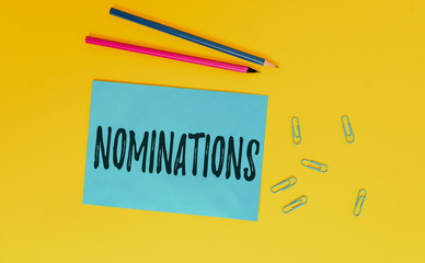 Conceptual hand writing showing Nominations. Concept meaning the act of officially suggesting someone for a job or position Blank paper sheet message reminder pencils clip colored background