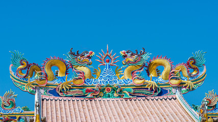 Elegant double golden dragon statue on the roof of Chinese shrine