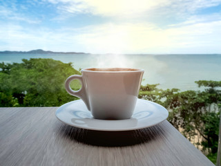 Close up a cup of black coffee on a wood table and sea-view background in the late morning of...