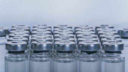 Glass medical ampoule vial for injection. Medicine is dry white drug penicillin powder or liquid with of aqueous solution in ampulla. Close up. Bottles ampule with aluminum cap on backgrounds gray.