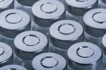 Glass medical ampoule vial for injection. Medicine is dry white drug penicillin powder or liquid with of aqueous solution in ampulla. Close up. Bottles ampule with aluminum cap on backgrounds gray.