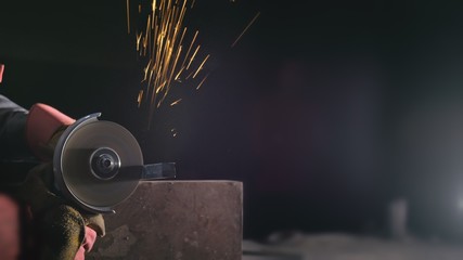 Forge workshop. Smithy manual production. Close up details of sparks, industrial worker using angle grinder and cutting steel. The blacksmith makes iron products for manufacture of fireplaces, stoves.