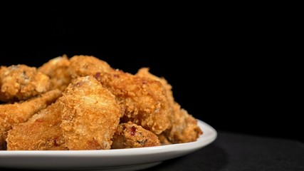 Cool beautiful fresh juicy cooked chicken wings in breading. Buffalo wings spread on food white plate in table. Very tasty and beautiful. Cooking with deep fryer fry machine.