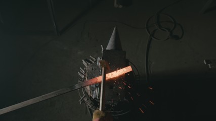 Forge workshop. Smithy manual production. Hands of smith with hammer hit on glowing hot metal, on...