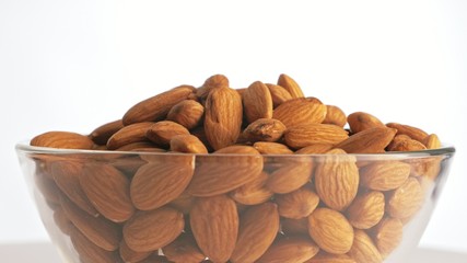 Nuts almond rotate are on a table in a plate. Snack in transparent dish on an isolated white...