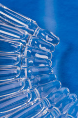 Glass medical ampoule vial for injection. Medicine is liquid sodium chloride with of aqueous solution in ampulla. Close up. Bottles ampule multicolor on background color and water. Human plasma.