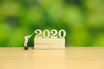 Miniature people - painter worker painting wooden number block, concept for happy new year 2020 with dreamy green background