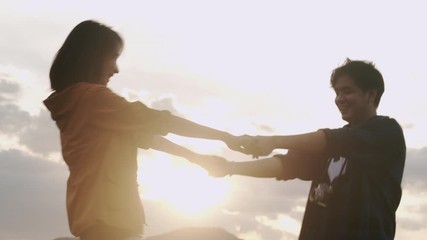 Medium shot. Happy couple of asian teenager in love romantic and fun.They start turning around  swirling holding hand laughing joyful and cheerful at the sunset