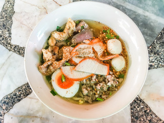 Popular Thai food and street food concept from Noodle Tom Yam, noodles with pork and hot spicy soup for lunch or dinner on wooden floor, Top view.