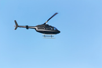 Black passenger helicopter on blue sky background