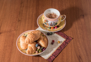 Croissants and cup of cappuccino coffee on wooden table