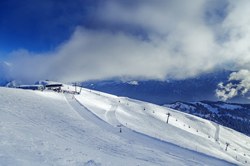 Mountain top lift station in ski resort Rosa Khutor in Russia. View of mountain slopes and sky with...