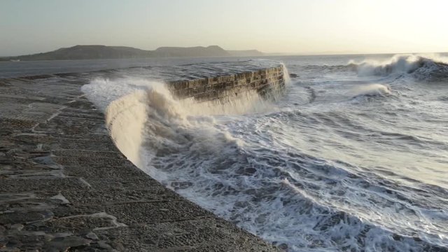 Big waves splashing on the Cobb in Lyme Regis, Dorset cused by gusty winds during high tide