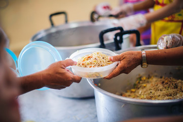 The hands of the poor receive food that volunteers share to alleviate hunger: the concept of donating food to the poor
