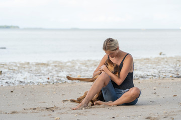 Fototapeta na wymiar Young woman with dog near sea water on the tropical beach on the island of Zanzibar, Tanzania, Africa