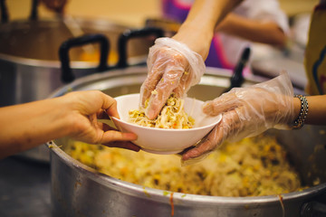 Food donation to the poor: The hands of the homeless are waiting to receive food from volunteers.