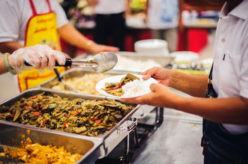 Food donation to the poor: The hands of the homeless are waiting to receive food from volunteers.