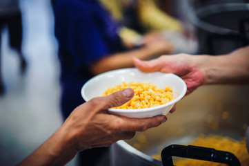 Food donation to the poor: The hands of the homeless are waiting to receive food from volunteers.