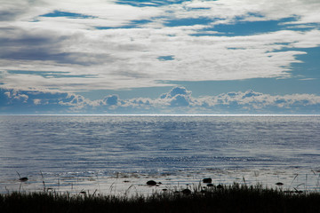 Seascape with dark foreground, blue water, blue sky and white clouds