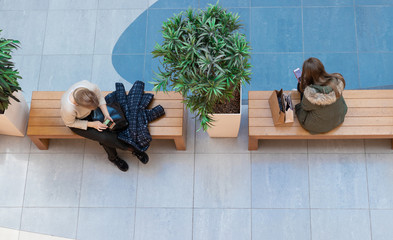 03/17/2009 Kiev, Ukraine, Sky Mall. People relax after shopping. They are sitting on a bench and looking at gadgets.