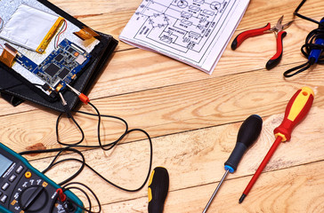 Disassembled tablet. Repair of modern broken electronic devices. Repair tools . Digital multimeter. Desktop appliances electronics. Schematic diagram of an electronic device.