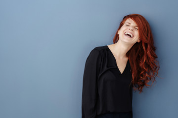 Young woman laughing uproariously at a joke - obrazy, fototapety, plakaty