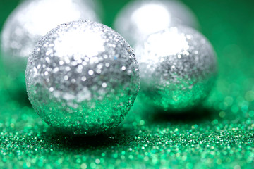 Macro abstract view of sparkling silver holiday baubles and ribbons on green glitter background with bokeh