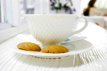 Closeup hot coffee in white coffee cup with cookies on white wooden table.
