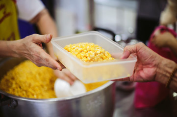 The concept of giving: Homeless people reach out to free volunteer meals from volunteers: help feed the hungry in society.
