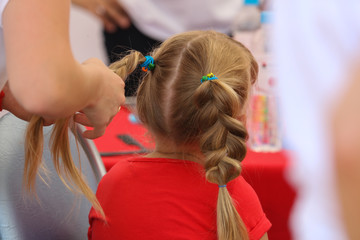 Naklejka premium Braiding braids on the head of a girl in the salon