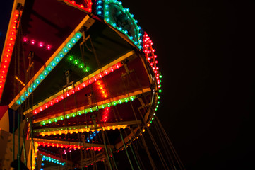 Children's Carousel at an amusement park in the evening and night illumination. amusement park at night. Outdoor vintage colorful carousel in the the city / carousel detail.