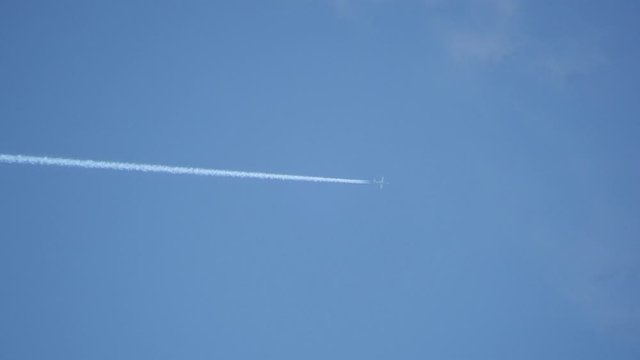 Closeup Of Jet Flying With Jet Stream Contrails In Blue Sky Through White Wispy Clouds