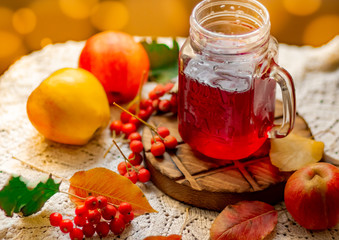Autumn composition of yellow leaves, apples and red berries on a white openwork napkin, red compote...