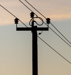 Electric pole with wires on a sunset background