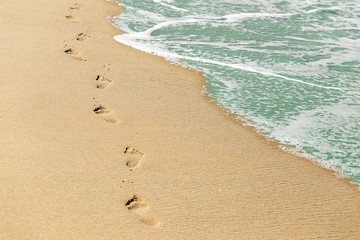 Beach, wave and footprints on sand. Vacation concept. Time, life passing concept.