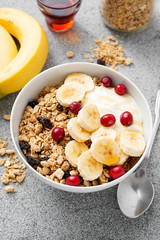 Healthy breakfast. Fresh granola, muesli with yogurt banana and cranberry on light gray background.
